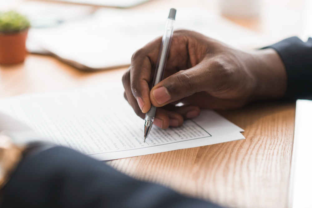 close up of a black buisness man's hand signing a contact